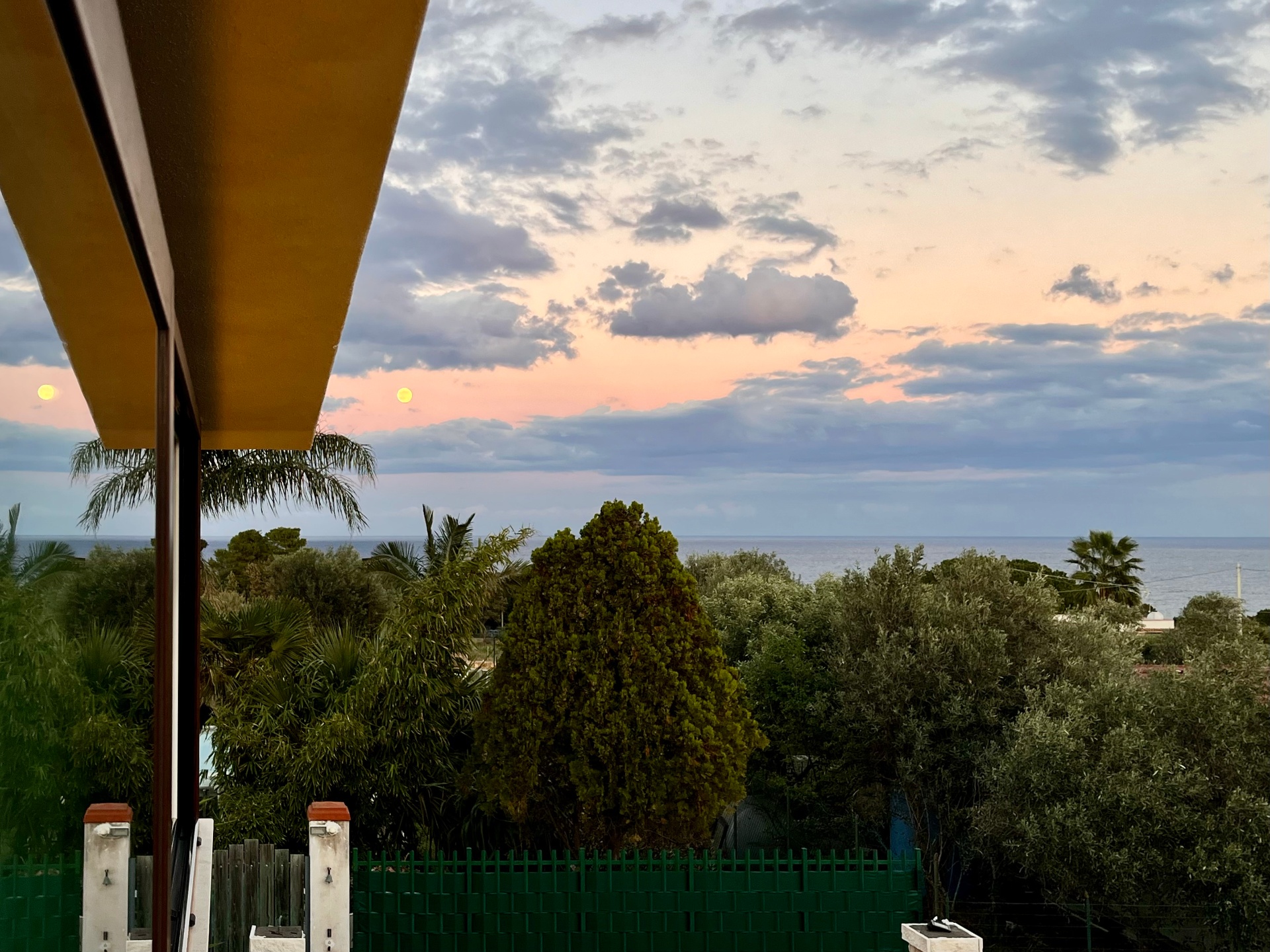Open blue window framing the Sicilian sea at dusk
